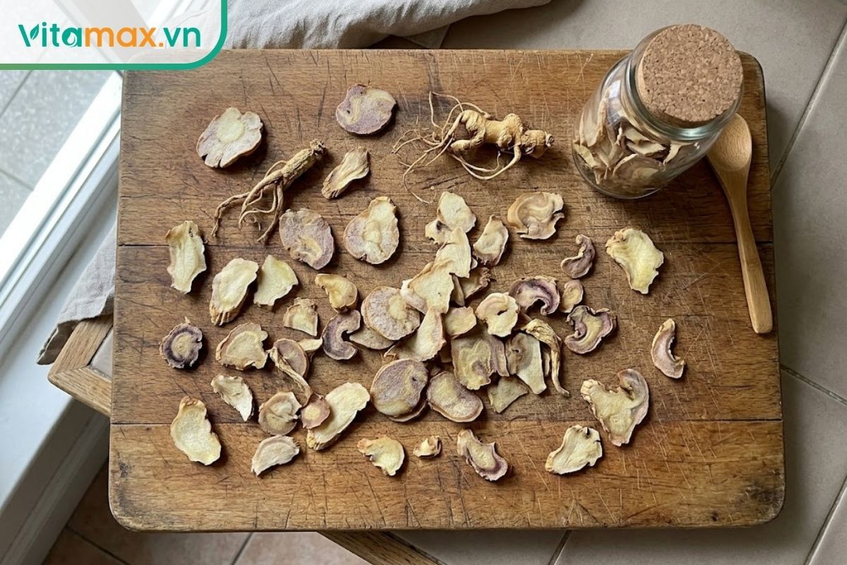 Các lát sâm Ngọc Linh sấy khô màu vàng nâu tự nhiên được đặt trên thớt gỗ, thể hiện rõ các vân củ và độ co ngót sau khi sấy.