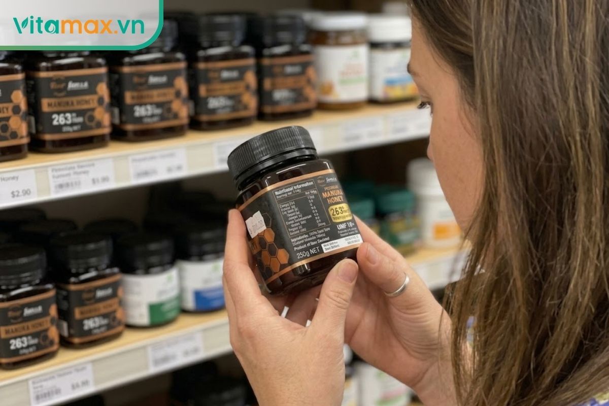 Khách hàng đang cầm lọ mật ong Manuka trên tay, chăm chú xem kỹ bảng thành phần và các chỉ số MGO, UMF in trên nhãn mác.