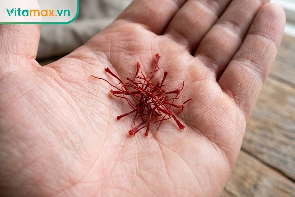 Chụp macro bằng điện thoại, cận cảnh những sợi nhụy hoa nghệ tây nguyên bản màu đỏ thẫm rực rỡ, khô ráo, đang nằm gọn trong lòng bàn tay.