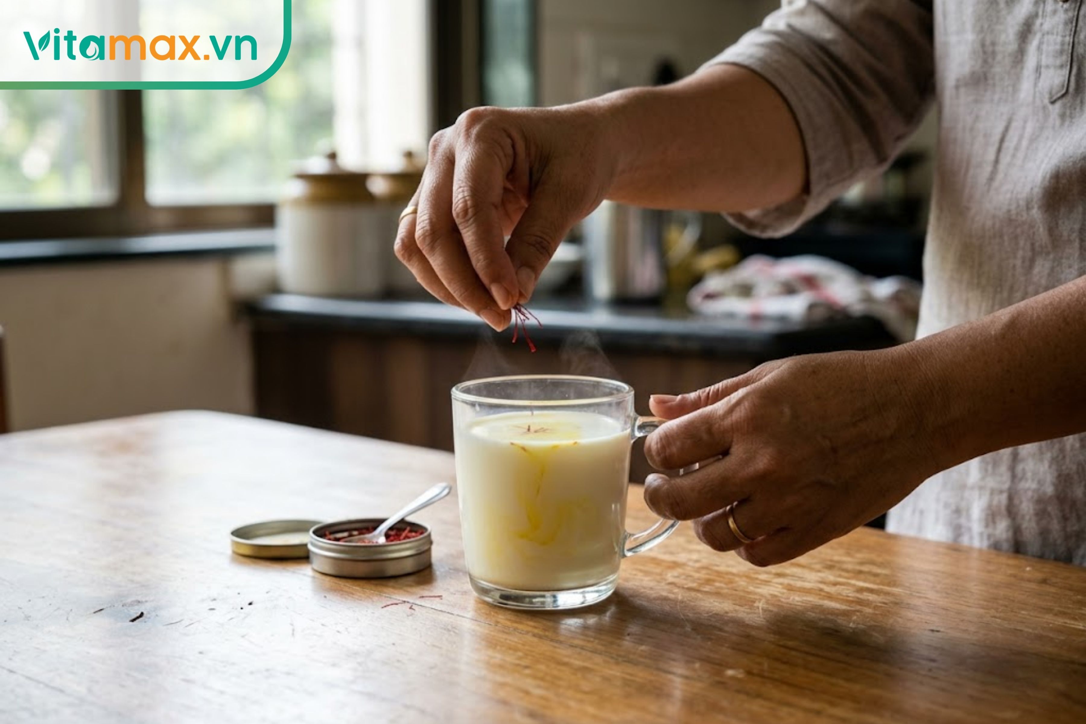 Thao tác thả vài sợi nhụy hoa nghệ tây vào cốc sữa ấm, màu vàng óng tự nhiên của saffron bắt đầu loang nhẹ ra sữa.