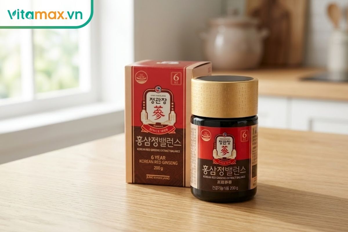 Hũ KGC Extract Balance 200g màu đen nắp vàng đặt cạnh hộp đỏ, thể hiện bao bì của dòng cao hồng sâm phối hợp mật ong và gừng.