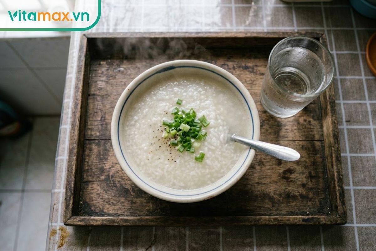Bát cháo trắng loãng nóng hổi rắc thêm chút hành lá đặt trên khay ăn mộc mạc dành cho người ốm.