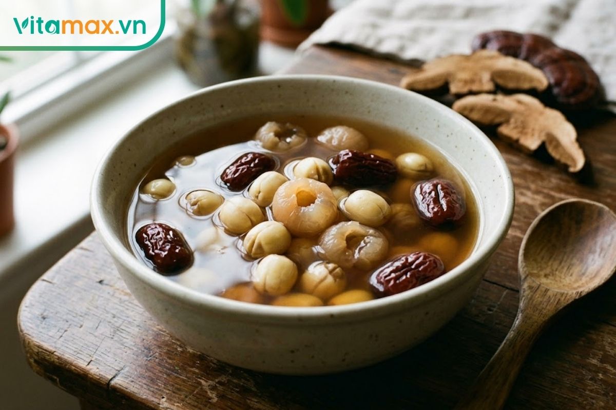 Bát chè linh chi với hạt sen, táo đỏ và long nhãn trong nước màu hổ phách, nguyên liệu mềm và phân bố tự nhiên.