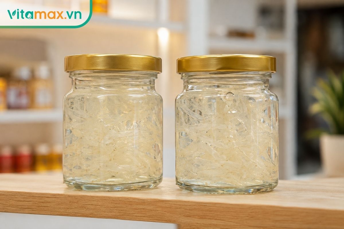 Hai hũ thủy tinh yến chưng sẵn đóng nắp kim loại màu vàng kim được đặt ngay ngắn trên kệ gỗ, chất lỏng bên trong trong suốt có lẫn sợi yến tự nhiên.