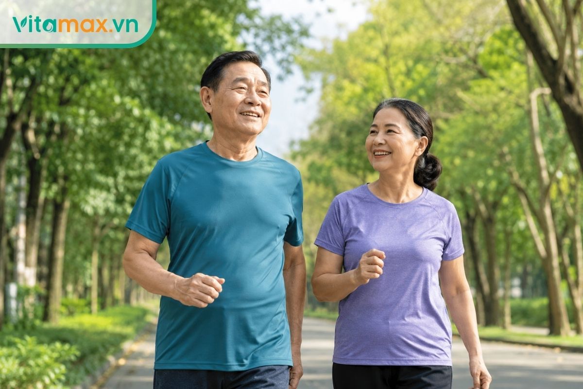 Hai người lớn tuổi người châu Á mặc trang phục thể thao đang mỉm cười đi bộ tập thể dục buổi sáng trong công viên nhiều cây xanh.
