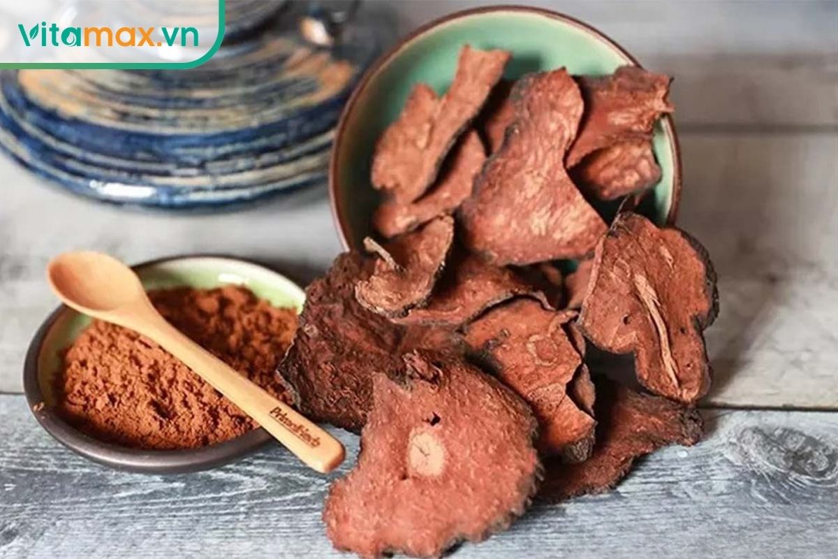 Các lát hà thủ ô đỏ khô màu nâu đỏ và bột dược liệu được bày trong bát nhỏ trên mặt bàn gỗ mộc.