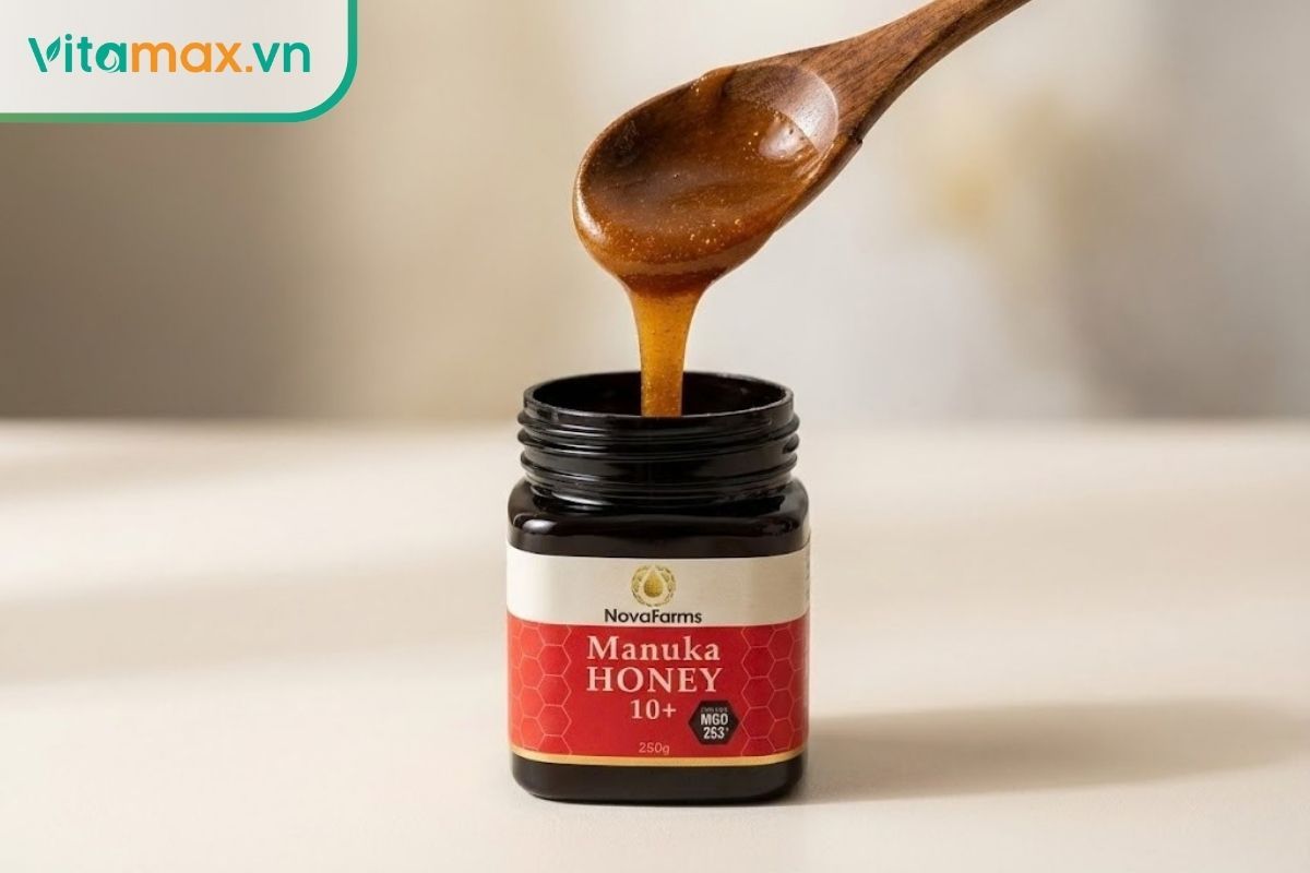Mật ong Manuka màu nâu sẫm đặc trưng với độ sánh quyện cao trên thìa gỗ.