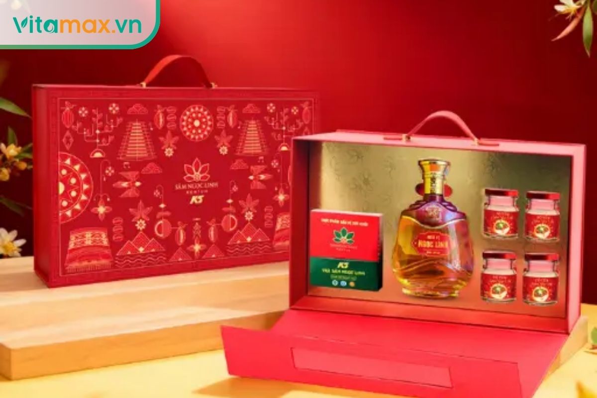 Hộp quà Tết màu đỏ sang trọng 'Hộp Quà Thiên Hoa' của Sâm Ngọc Linh K5 mở ra, bên trong có chai rượu sâm, 4 hũ yến sâm và 1 hộp trà sâm, đặt trên bàn gỗ.
