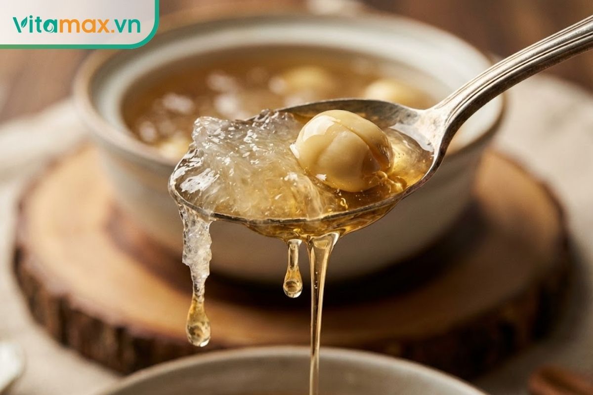 Cận cảnh thìa đang múc yến chưng cùng hạt sen bở mềm, thể hiện độ sánh ngon của mật ong.