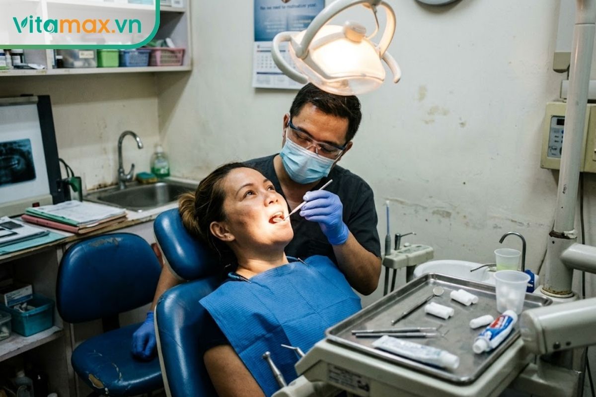 Bác sĩ nha khoa đang dùng gương soi nha khoa kiểm tra khoang miệng cho bệnh nhân thực tế tại phòng khám.