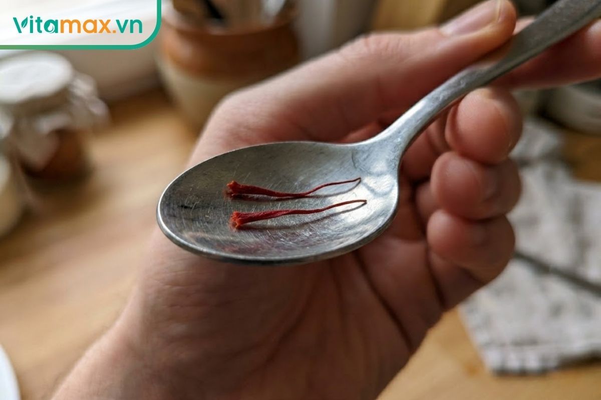 Cận cảnh 2 sợi nhụy hoa nghệ tây nguyên chất trên chiếc thìa cà phê nhỏ.