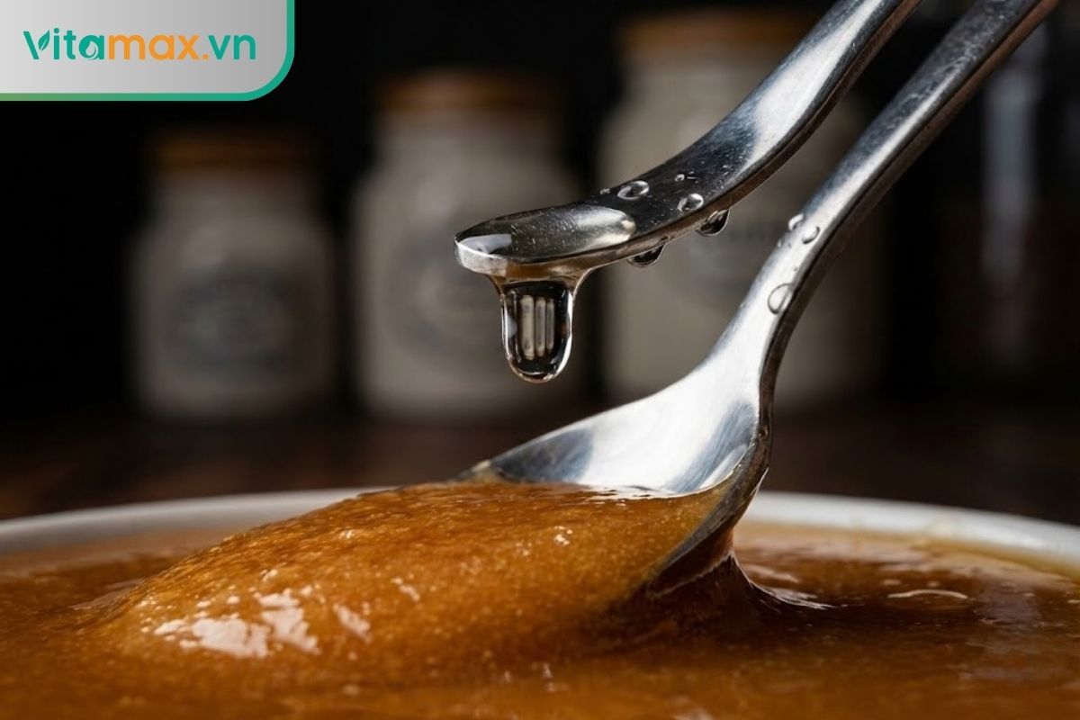 Cận cảnh thìa inox dính nước đang đưa vào hũ mật ong Manuka gây nguy cơ lên men.