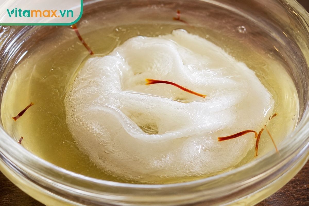 Cận cảnh viên mặt nạ giấy nén đang từ từ nở bung ra khi hút dung dịch nước hoa hồng ngâm nhụy hoa nghệ tây màu vàng nhạt.