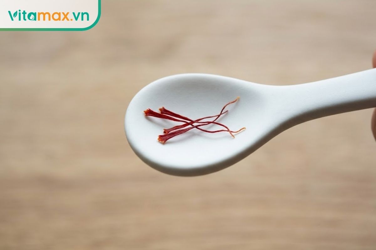 Một chiếc thìa sứ trắng nhỏ xíu chứa đúng 4 sợi nhụy hoa nghệ tây màu đỏ, minh họa cho lượng sử dụng cực kỳ an toàn mỗi lần pha.