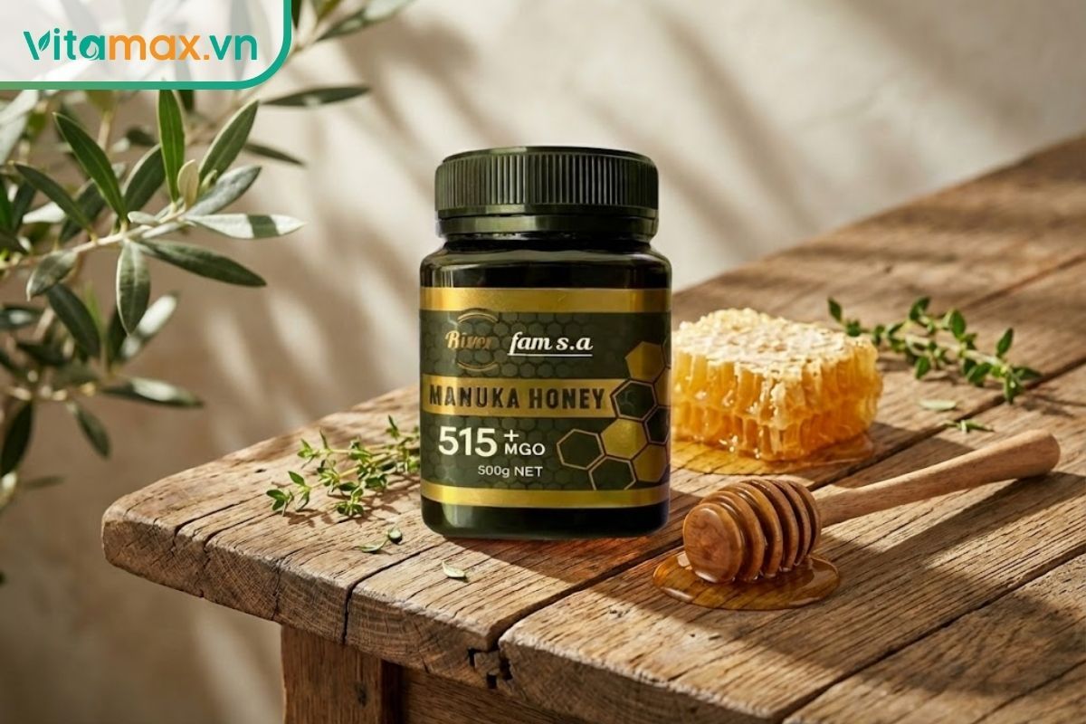 Một hũ mật ong Vitamax cao cấp đặt cạnh sáp ong tự nhiên và dụng cụ lấy mật bằng gỗ trên bàn ăn tràn ngập ánh nắng.