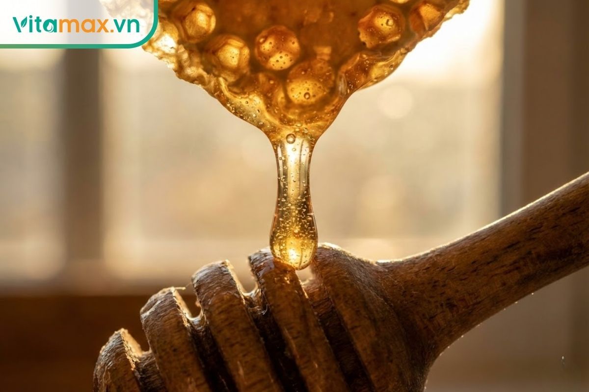 Cận cảnh mật ong nguyên chất màu vàng hổ phách đang chảy mượt mà từ sáp ong tự nhiên, thể hiện độ sánh và độ tinh khiết.