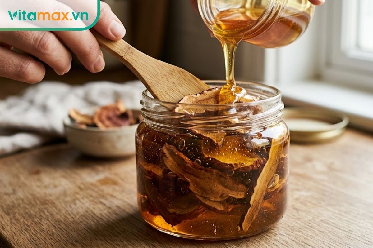 Các lát nấm linh chi khô nằm chìm hoàn toàn trong mật ong bên trong hũ thủy tinh sạch, khô và có nắp kín.