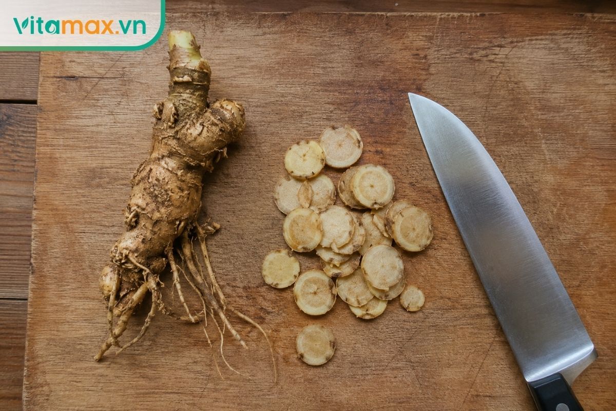 Củ sâm Ngọc Linh tươi đặt trên thớt gỗ, một nửa củ đã được dao thái thành các lát rất mỏng để chuẩn bị ngâm mật ong.
