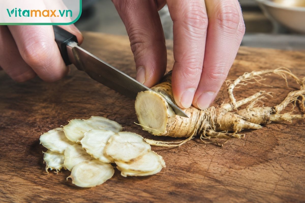 Cận cảnh một bàn tay đang dùng dao sắc thái củ sâm thành những lát tròn thật mỏng trên thớt gỗ, lộ rõ vân sâm tươi màu vàng nhạt bên trong.