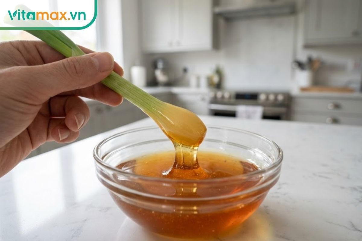 Góc nhìn người thứ nhất: bàn tay đang cầm cọng hành nhúng ngập vào chén mật ong để kiểm tra độ thật giả.
