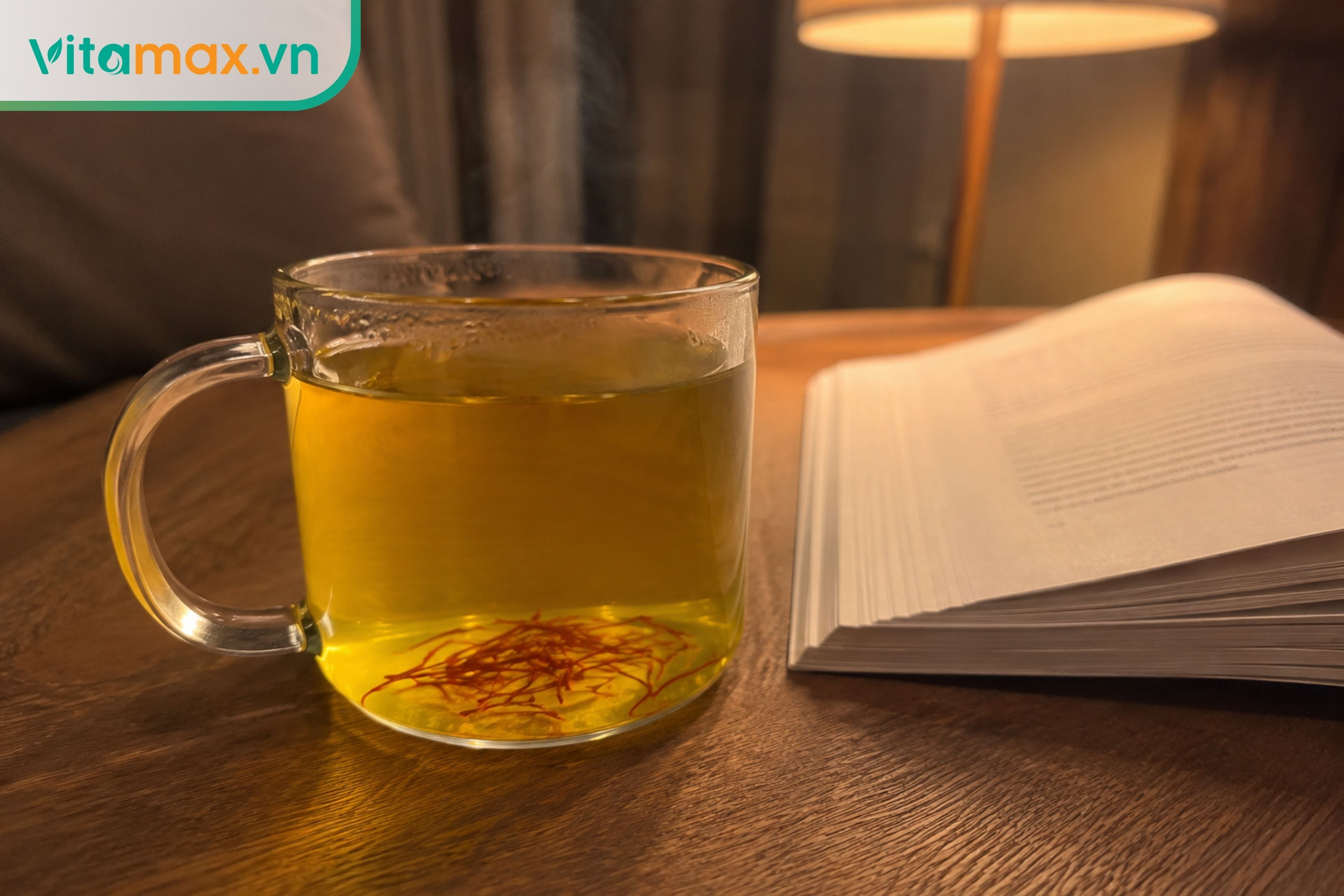 Ly trà saffron ấm màu vàng óng đặt trên bàn cạnh giường ngủ, thói quen uống vào buổi tối giúp thư giãn và ngủ ngon.